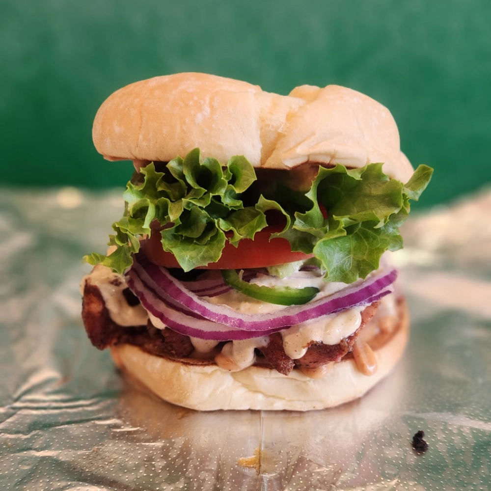 A smoked chicken sandwich with aioli, onions, and lettuce